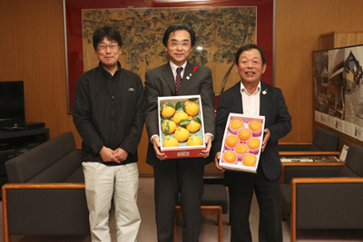 柑橘類の箱を持って並ぶ永松市長とJA職員