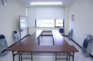 机がロの字に並べられている第6研修室の内観写真